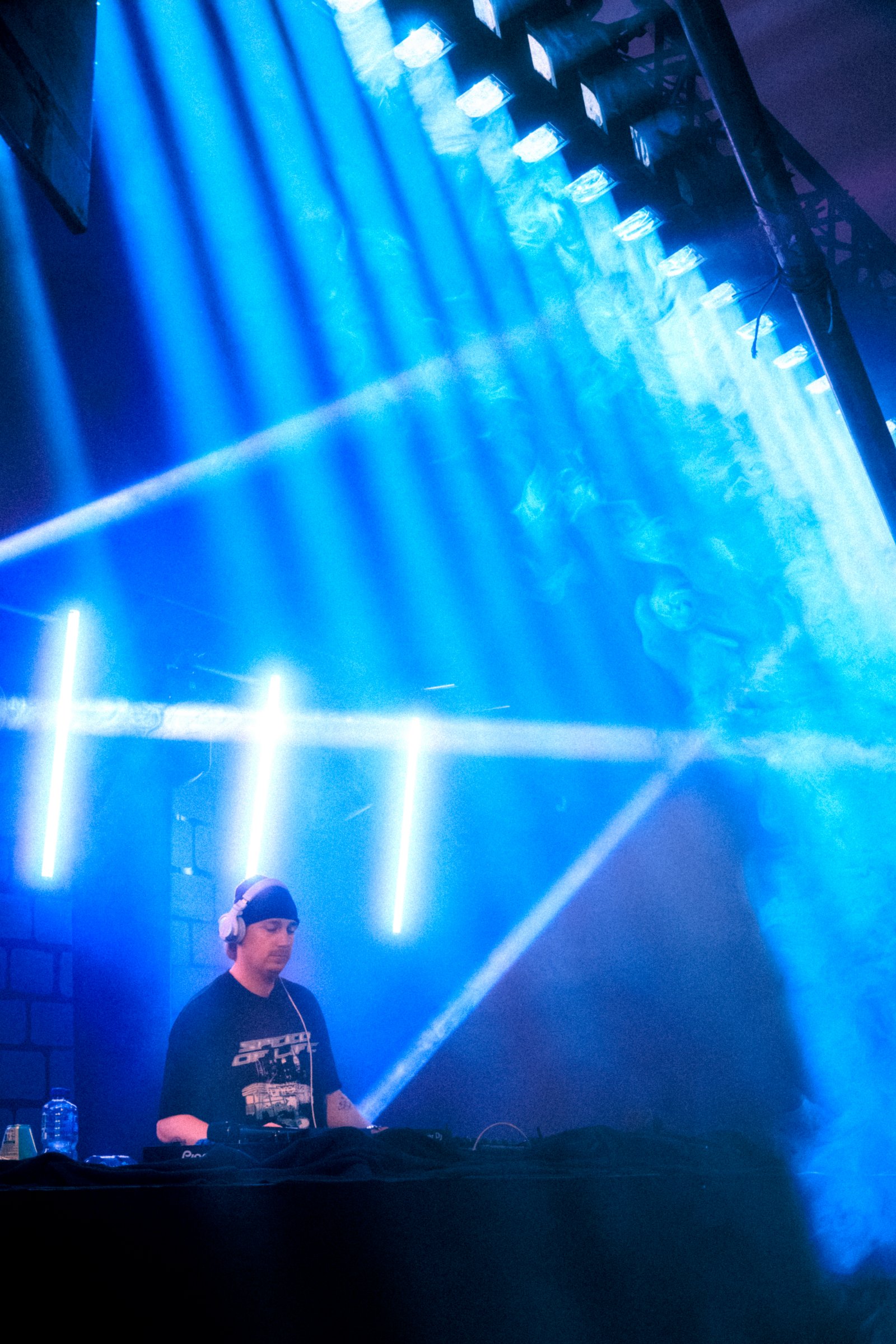 Een dj achter de draaitafels onder blauwe podiumverlichting