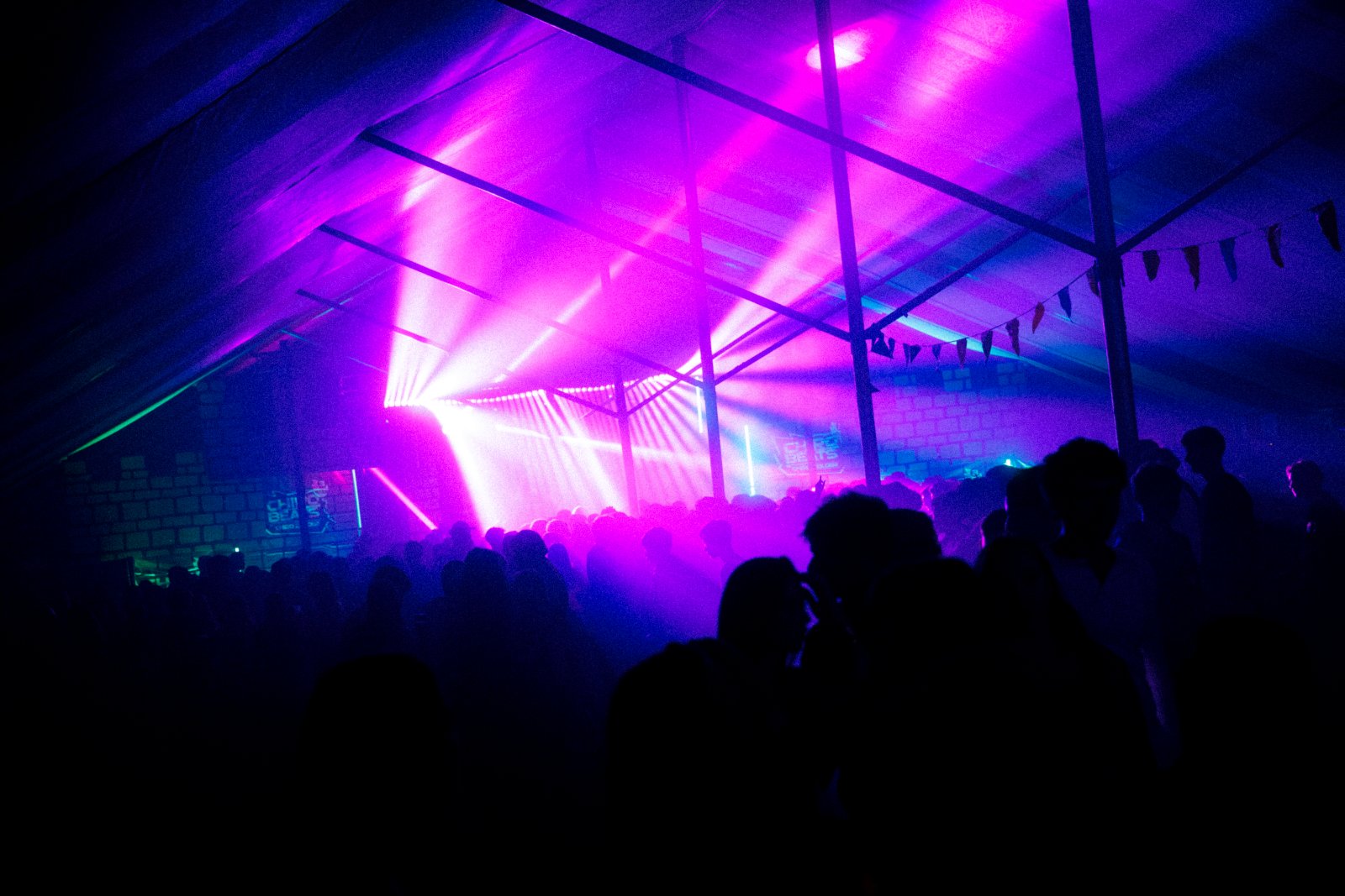Roze lichtbundels boven het publiek in de feesttent
